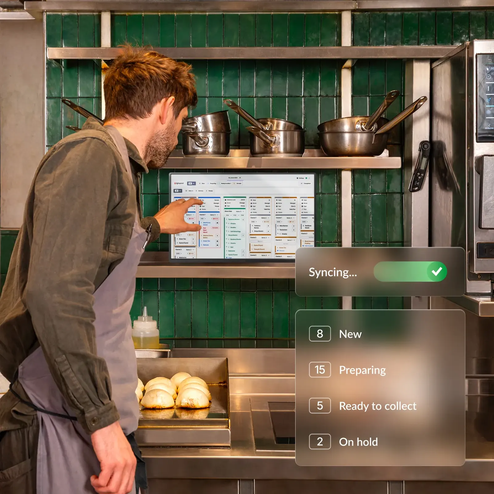 Cook touching a kitchen display screen with orders syncing