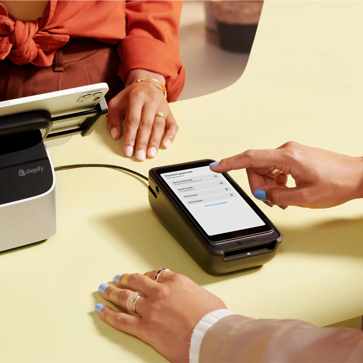 Hands tapping a card on a handheld card reader at a counter