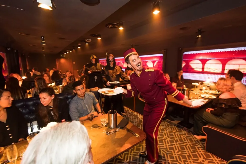 Busy bar and restaurant with a costumed host leaning over a table
